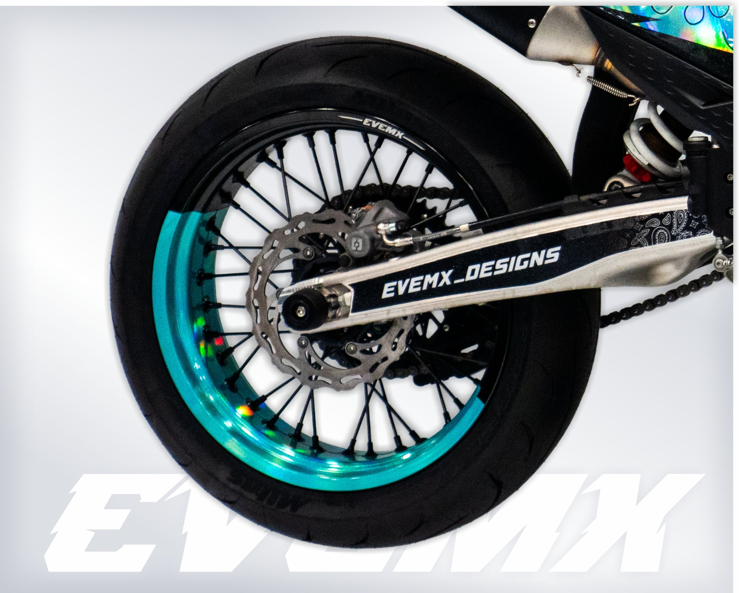 Motorcycle wheel with turquoise rim and 'EVEMX DESIGNS' branding on a white background